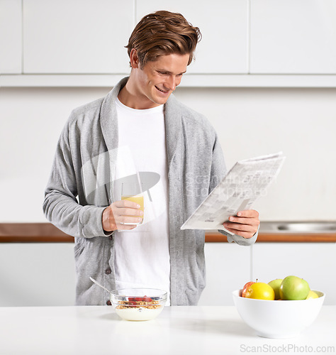 Image of Breakfast, juice and man with newspaper in kitchen for information at modern apartment. Nutrition, cereal and young male person drinking healthy beverage and reading public journalism at home.