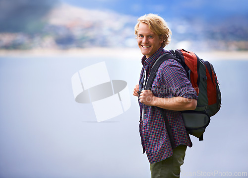 Image of Man, hiking and portrait in nature for travel, adventure and wellness by ocean, sea and vacation in Europe. Face of an happy and young person with backpack for trekking, explore and outdoor journey
