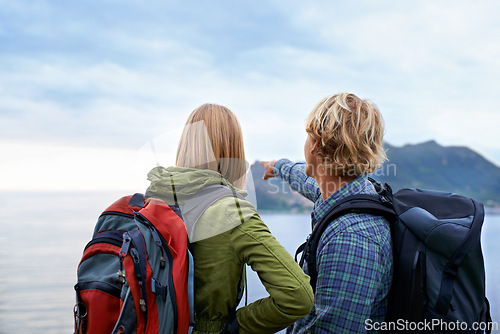 Image of Hiking, nature and couple on mountain pointing with backpack for freedom, trekking or explore landscape. Travel, dating and man and woman hug by scenic view on holiday, vacation and outdoor adventure