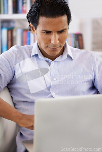 Image of Businessman, laptop and reading on sofa in home for remote work, research and online planning in living room. Entrepreneur, person and technology with corporate project, communication and web surfing