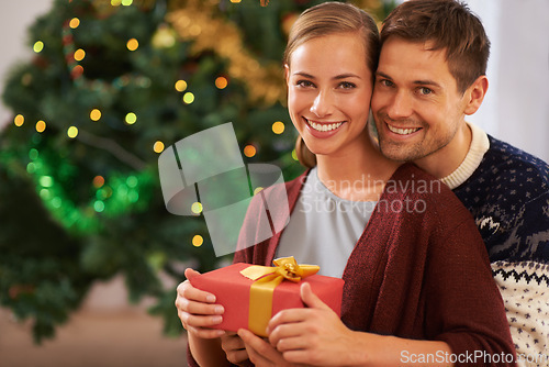 Image of Happy, Christmas gift and portrait of couple in living room at home for festive celebration. Smile, love and young man and woman with holiday present box for xmas event or party at modern house.