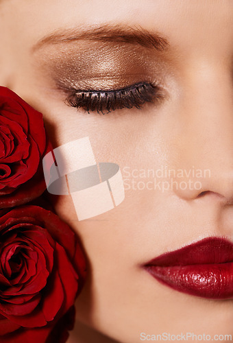 Image of Closeup of face, makeup and beauty with roses, red lipstick and gold eyeshadow with lashes for cosmetics. Shimmer, shine and bold aesthetic, romantic flowers and cropped with skin and cosmetology