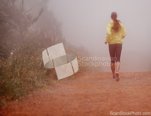 Image of Woman, rear view and running in woods with exercise for fitness, morning routine and workout with fog and legs. Athlete, person and cardio with sportswear on outdoor trail and forest for wellness