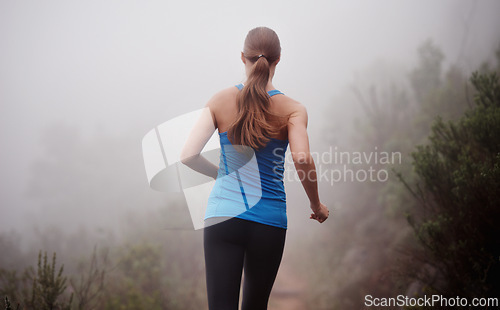 Image of Woman, rear view and running in woods with workout for exercise, morning routine and fitness with fog and mist. Athlete, person and cardio with sportswear on outdoor trail and forest for wellness