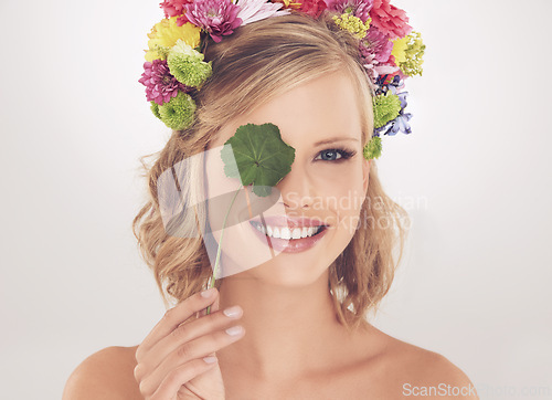 Image of Woman, portrait and happy with flowers on crown in studio with makeup and leaf for cosmetics and skincare. Spring aesthetic, model and face or smile with floral headband or beauty on white background