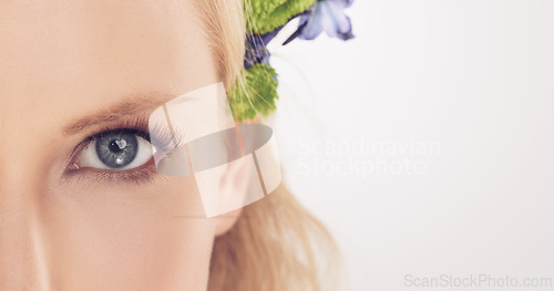Image of Woman, flowers and half face in studio with beauty, makeup or cosmetics with eyelash extensions on mockup space. Model, person and portrait with collagen, skincare or glowing skin on white background