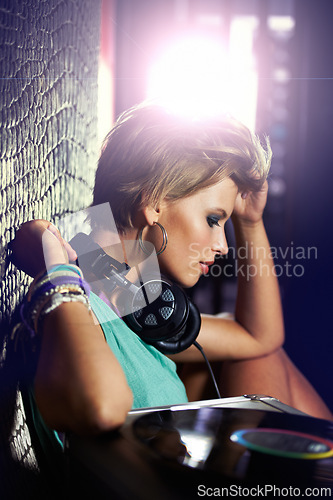 Image of Nightclub, DJ and woman with headphones for listening to music with vinyl turntable and tech. Techno, rave and musician in light at concert stage and mix sound for party event entertainment at night