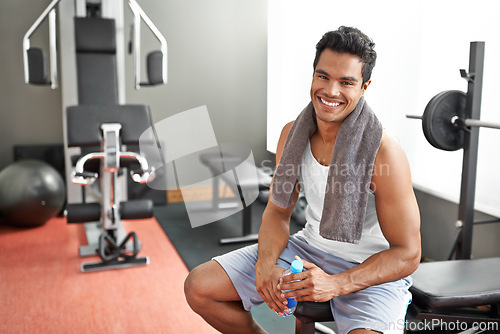 Image of Gym, portrait and happy man with water bottle for recovery after exercise and body building. Healthy, fitness and person relax after workout with liquid hydration for benefits to muscle and wellness