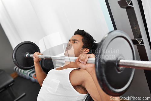 Image of Bench, press and man at gym for workout, exercise and body building in Mexico. Healthy, person and weightlifting challenge for strong muscle, fitness or progress in training arms with barbell at club