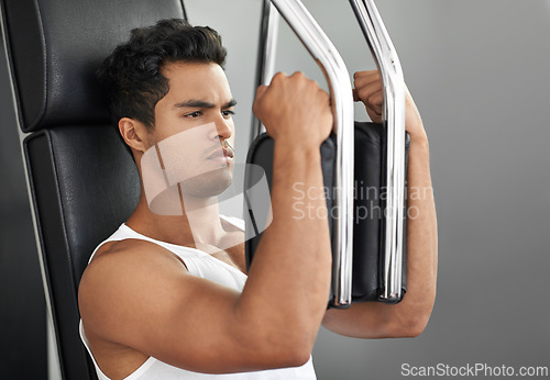 Image of Fitness, chest exercise machine and man in studio isolated on gray background for muscle workout. Exercise, health or wellness and serious young bodybuilder athlete training with equipment at gym