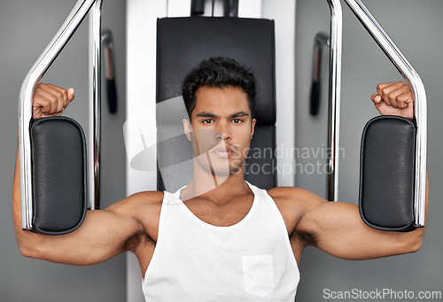 Image of Portrait, resistance exercise and man in gym for arm muscle training for health, wellness and strength. Fitness, body and young male athlete on machine with weights for bodybuilding in sports center.