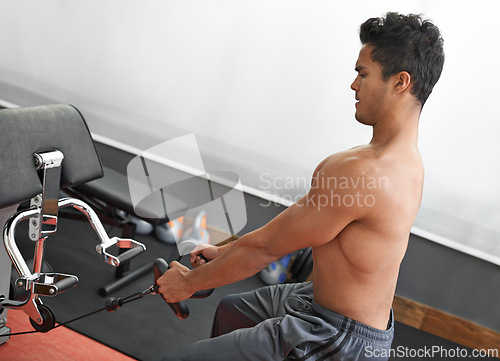 Image of Fitness, rowing machine and shirtless man in gym for health, wellness or bodybuilding workout. Exercise, strong and focus with body of young bodybuilder athlete training on equipment for improvement
