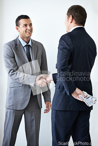 Image of Happy businessman, money and handshake with bribe for agreement or deal on a white studio background. Man, colleagues or employees shaking hands with cash, bills or paper for secret, bribery or fraud