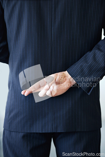 Image of Businessman, back and fingers crossed with luck for hope, confidential or secret on a studio background. Closeup or rear view of man or business employee hiding hand in conspiracy, lie or corruption