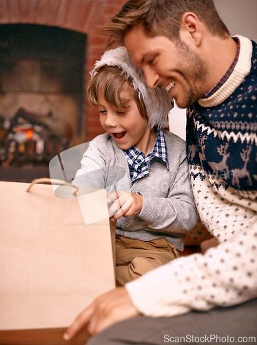 Image of Father, son and opening gift on Christmas, curiosity and happy for celebrating a festive holiday. Daddy, child and bonding on religious vacation in living room, childhood and tradition of present