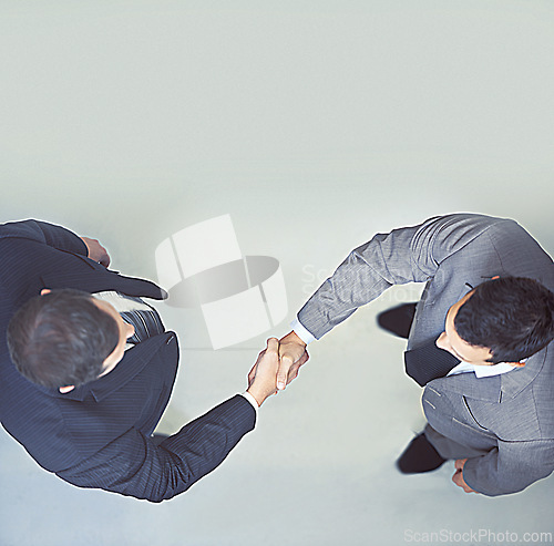 Image of Businessman, handshake and partnership above for agreement, deal or meeting on a gray studio background. Top view of man, colleagues or employees shaking hands for b2b or teamwork on mockup space