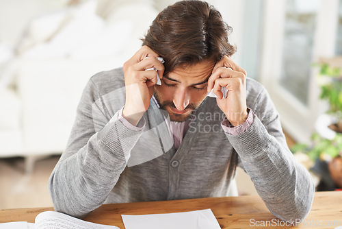 Image of Writer, man and stress in home office with paper on desk, headache and worried to meet deadline. Author, procrastination and frustrated with work on research for information, writing tips for story