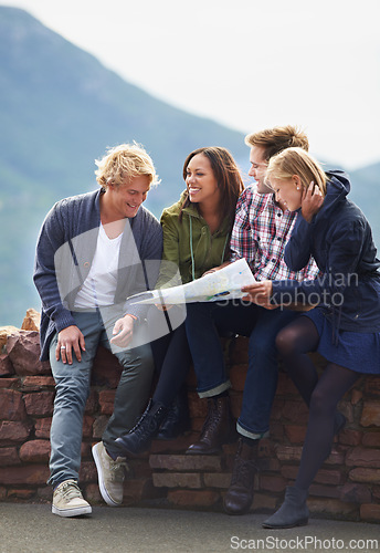 Image of Happy people, friends and map for direction, location or planning next destination on stone wall. Young group looking or checking route, path or paper on holiday weekend or outdoor vacation in nature