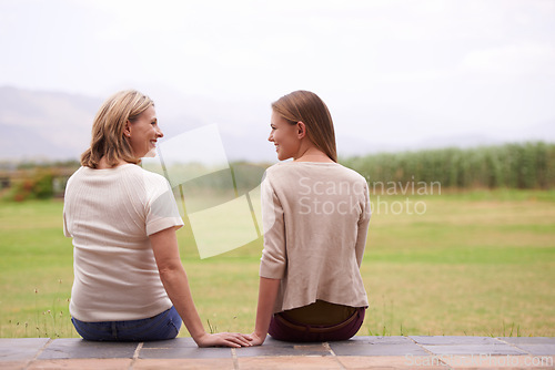 Image of Women, mother and daughter with garden, back and conversation in morning with bonding, love and care. People, girl and family for talking, chat or relax together on patio by grass lawn in countryside