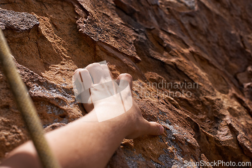 Image of Person, hand and rock climber with rope on mountain for climbing, hiking or grip in extreme sports. Closeup of hiker or mountaineer grabbing patch, hole or pattern on natural surface for fitness