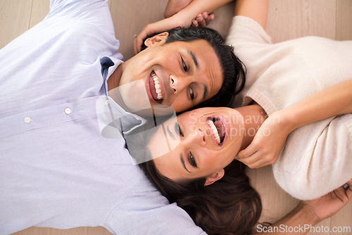 Image of Top view, couple and laughing on floor in living room, relaxing and bonding together in romantic relationship. Above, man and woman laying on ground with happy, marriage and playful people at home.