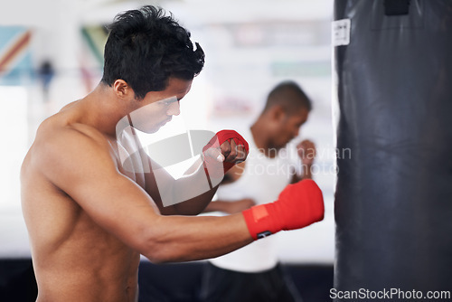 Image of Punching bag, man and boxing fitness with at a gym for training, resilience or performance training. Sports, body and male boxer profile with punch practice for strength, energy for fighting exercise