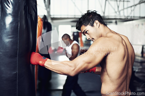 Image of Fitness, punching bag and man with boxing gloves at a gym for training, resilience or performance. Sports, body and male boxer profile with punch practice for strength, energy for fighting exercise
