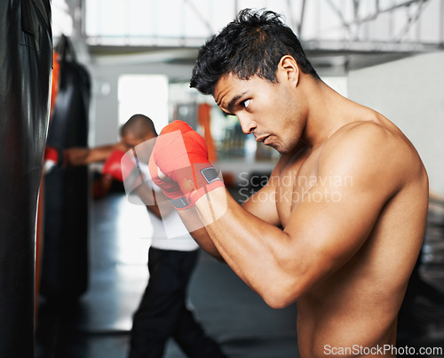 Image of Punching bag, fitness and man with boxing gloves at a gym for training, resilience or performance. Sports, body and male boxer profile with punch practice for strength, energy for fighting exercise