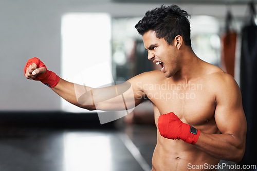 Image of Man, training and angry in gym for boxing match, practice and determined for competition to win. Light weight champion, workout and focus for tough sport, fitness and exercise with aggression for mma