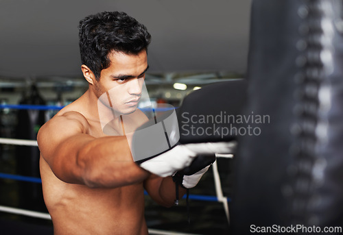 Image of Sports, serious and man boxer in gym for exercise, workout and combat training for competition. Cardio, health and shirtless male athlete fighter in boxing ring with gloves in fitness center.