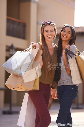 Image of Women, happy and shopping bag in city for fashion, sale and discount with portrait outdoor in Europe. Young people or friends with smile and diversity for retail purchase, travel and style or clothes