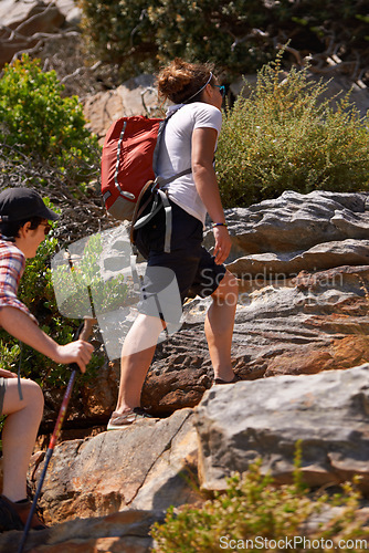 Image of Woman, friends and hiking up mountain with backpack on rocky trail or outdoor path in nature. Active female person or hiker walking or climbing for trekking, fitness or adventure together outside