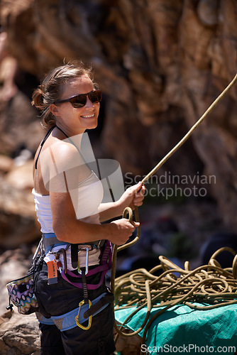 Image of Mountain, rock and woman with smile for climbing with rope, cliff and active for fitness and outdoor. Adventure, fearless and girl with gear for extreme sport in nature with happiness and brave