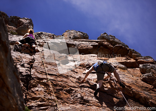 Image of Hikers, rock climbing and outdoors for adventure, fitness and exercise in the sun for extreme sports. People, climb wall and nature for wellness, mountain and fearless activity for strength