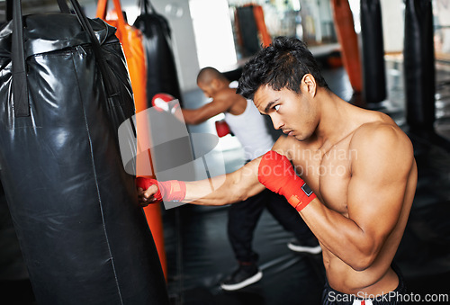 Image of Punching bag, man and fitness with boxing gloves at a gym for training, resilience or performance. Sports, body and male boxer profile with punch practice for strength, energy for fighting exercise