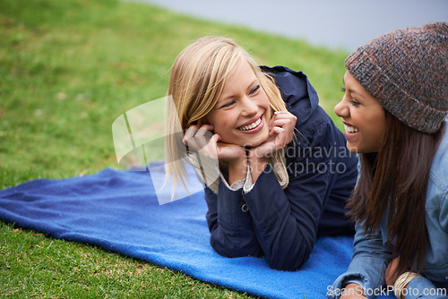 Image of Happy, friends and relax on blanket for picnic outdoor in summer on holiday or vacation together. Women, smile and laugh in conversation in park, woods or lying on grass in backyard or garden