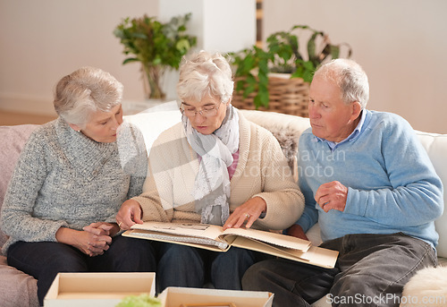 Image of Old people, friends and photo album for memory talking in retirement on sofa together, photograph or connection. Elderly man, women and picture book in home in Canada for nostalgia, remember or love