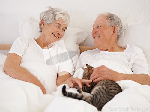 Image of Mature couple, bed and cat for bonding, embrace and love in morning for smile and cuddle. Senior man, woman and kitty pet, happy and retirement to enjoy marriage and old people in bedroom at home