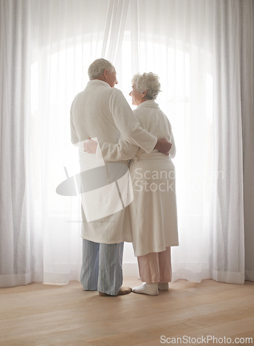 Image of Senior couple, hug and relaxing by window in retirement, love and bonding in pajamas on holiday. Elderly people, back and embracing for affection in marriage, romance and morning routine at home