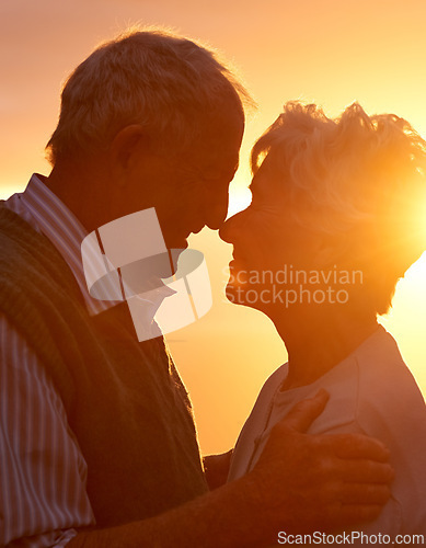 Image of Sunset, elderly couple and embrace outdoor, love and bonding for connection together in nature. Man, woman and touch forehead for care, romance or support for commitment to relationship in retirement