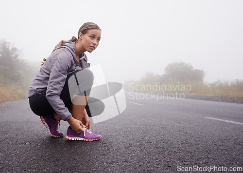 Image of Fitness, woman and tie shoes on road outdoor to prepare for exercise, training or workout with fog in winter. Sports, serious person and tying sneakers, thinking and getting ready on mockup space