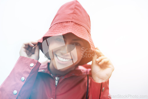 Image of Happy woman, portrait and red rain jacket with hat for weather, cloudy sky or winter season in outdoor storm. Face of female person with waterproof coat and smile for protection, fog or cold overcast