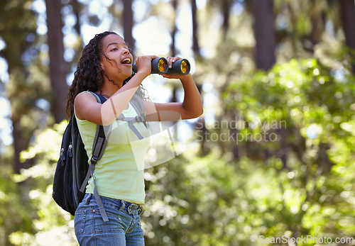 Image of Happy girl, binoculars and nature with backpack for sightseeing, explore or outdoor vision. Young female person, child or teenager enjoying sight, adventure or bird watching and search in forest