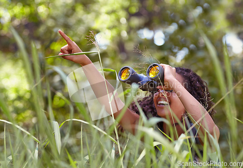 Image of Nature, binoculars and girl in grass for exploring in park on vacation, adventure or holiday. Travel, forest and young child or kid with equipment in lawn in outdoor field or woods on weekend trip.