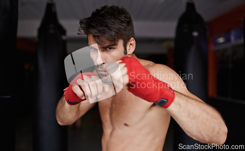 Image of Man, portrait and practice for boxing in gym, fitness and topless for exercise and workout. Male person, bodybuilder and punching bag for challenge or athlete, training and serious for competition