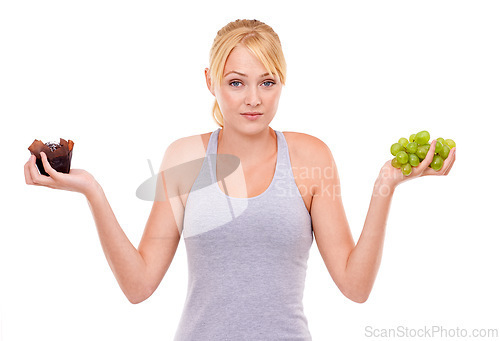 Image of Woman, confused and dessert or fruit in studio with white background in backdrop. Girl, choice and decision between muffin or grapes for nutrition in food, care and healthy diet for weight loss