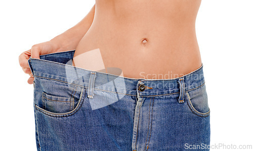 Image of Diet, body and woman with big pants in studio for weight loss, fitness or exercise results. Wellness, health and closeup of female person with jeans for measuring slim stomach by white background.