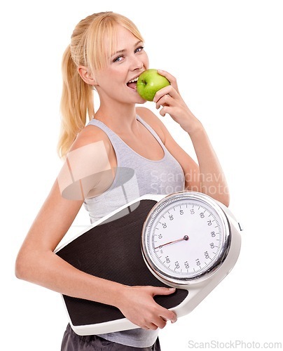 Image of Portrait, scale and woman with apple for progress, diet benefits or food to lose weight in studio. Healthy eating, nutrition and happy girl with fruit for weightloss, digestion and white background