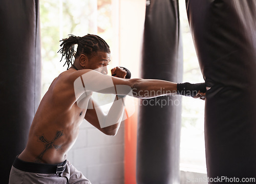 Image of Fitness, punching bag and black man in gym for exercise, boxing challenge or competition training. Power, muscle and serious champion boxer at workout with confidence, fight and energy in sports club