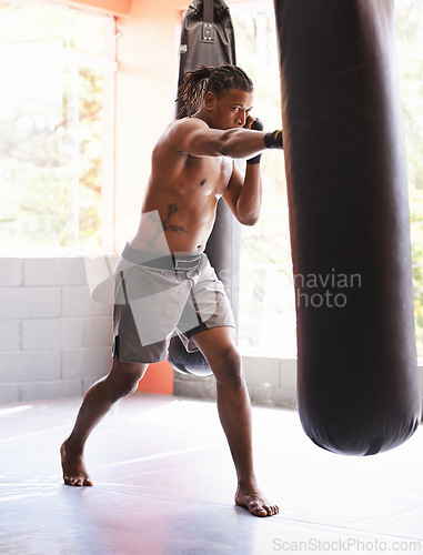 Image of Fitness, punching bag and black man in gym for body exercise, boxing challenge or competition training. Power, muscle and champion boxer at workout with confidence, fight and energy in sports club.